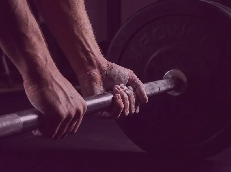 ידיים אוחזות במוט משקולות באימון כוח
